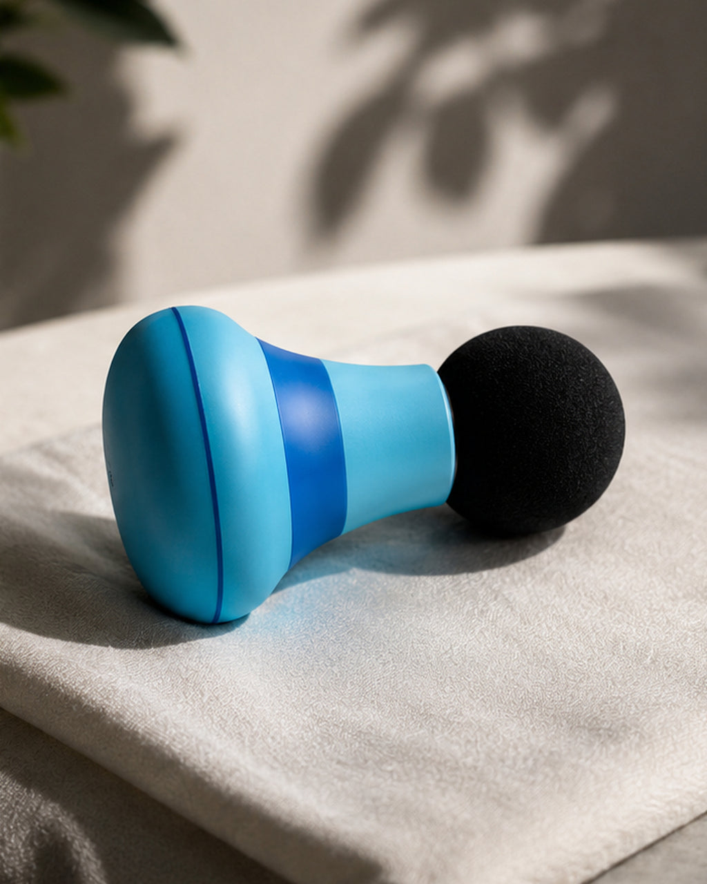 Mini masajeador azul de perfil sobre una toalla