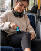 Mujer usando el mini masajeador en la pierna en el autobus